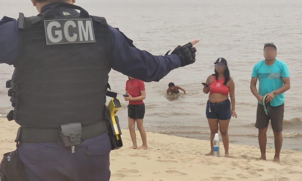 Descumprindo interdição, grupo de banhistas é orientado a sair da praia da Ponta Negra na extrema vazante do rio