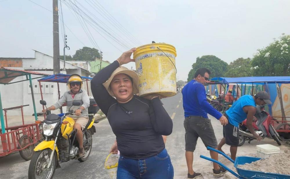 Entre homens, mulher carrega quilos de areia para faturar uma grana extra no Dia de Finados